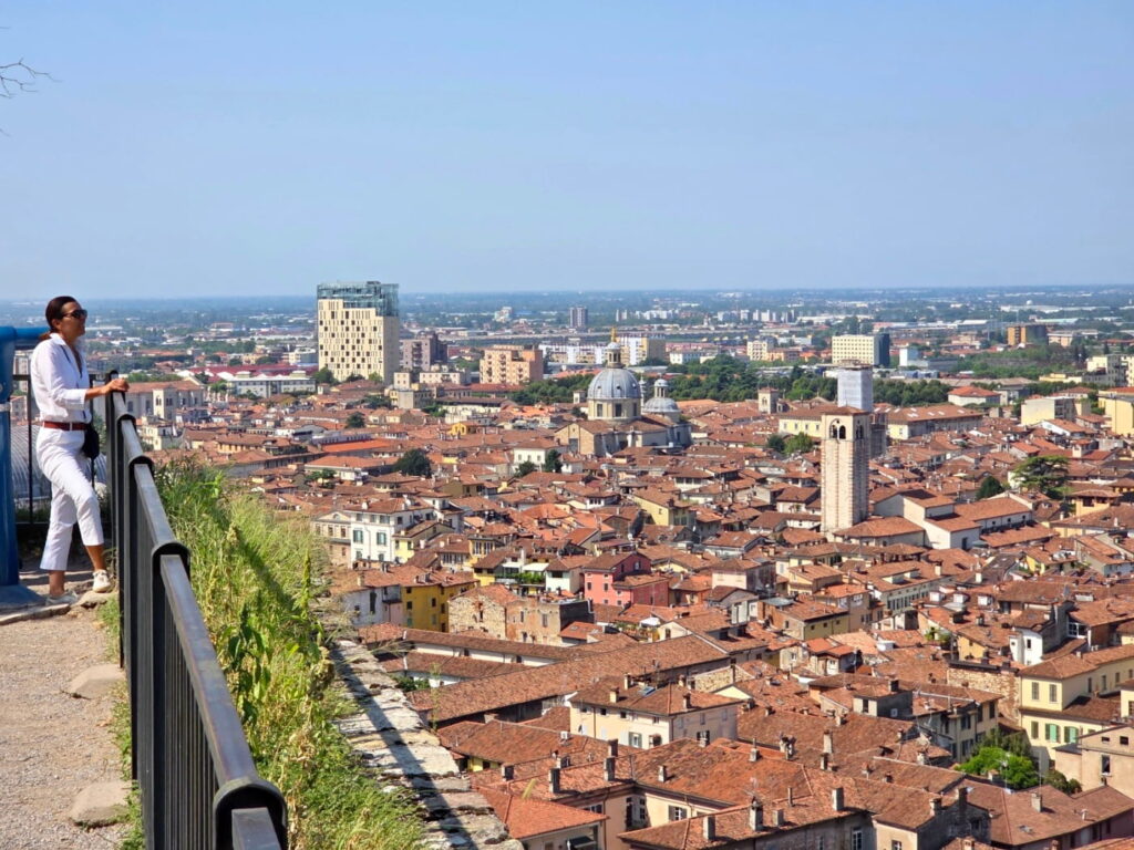 Brescia city view from castle viewpoint with visitor overlooking rooftops, Italy