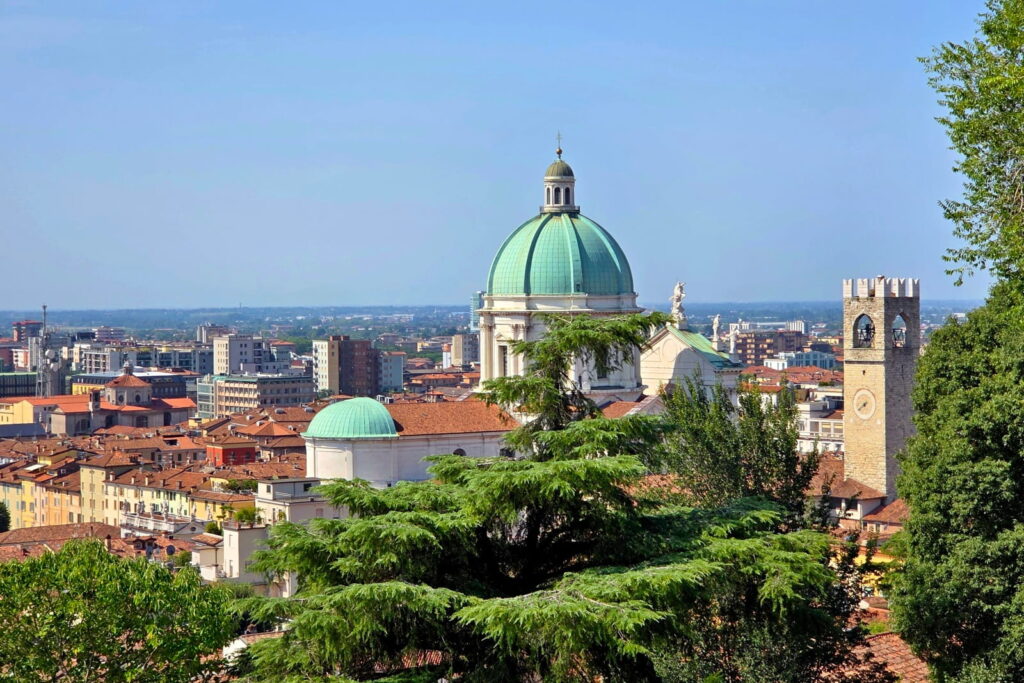 View over Brescia, Italy, featuring the green dome of the New Cathedral and the Torre del Popolo from the castle hill.