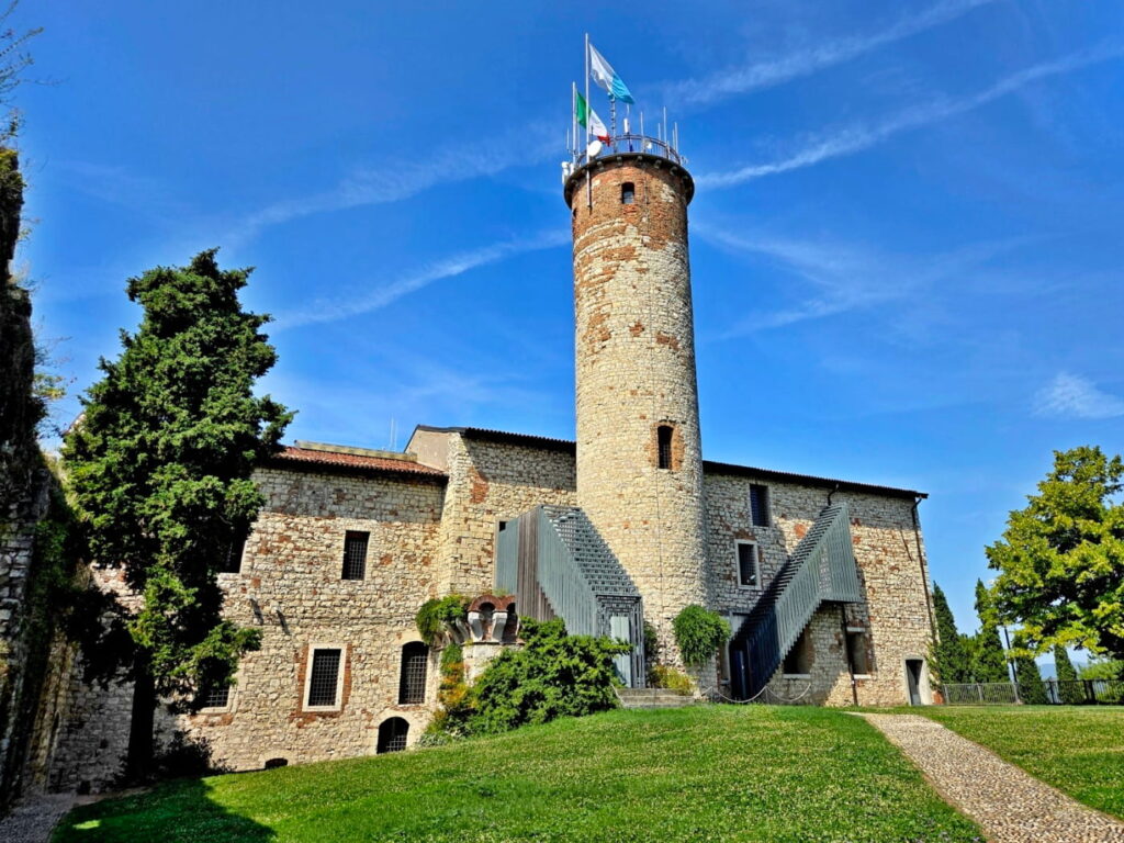 Brescia Castle tower and stone walls with flags on top, Italy