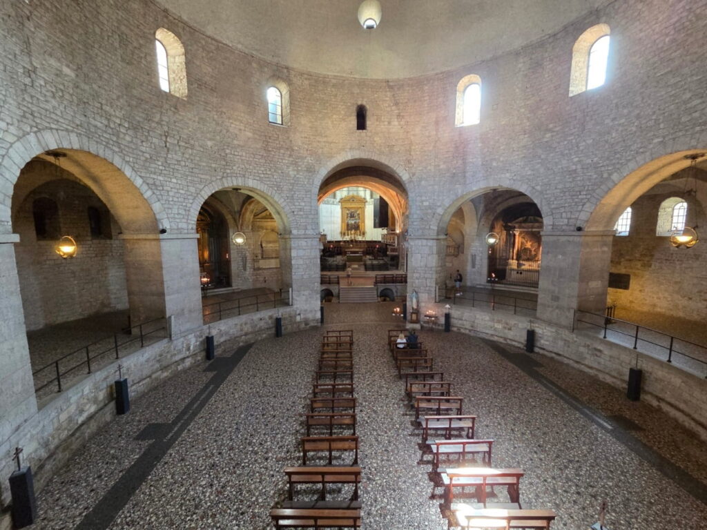 Interior of Duomo Vecchio in Brescia, Italy, with circular nave, stone arches and central altar