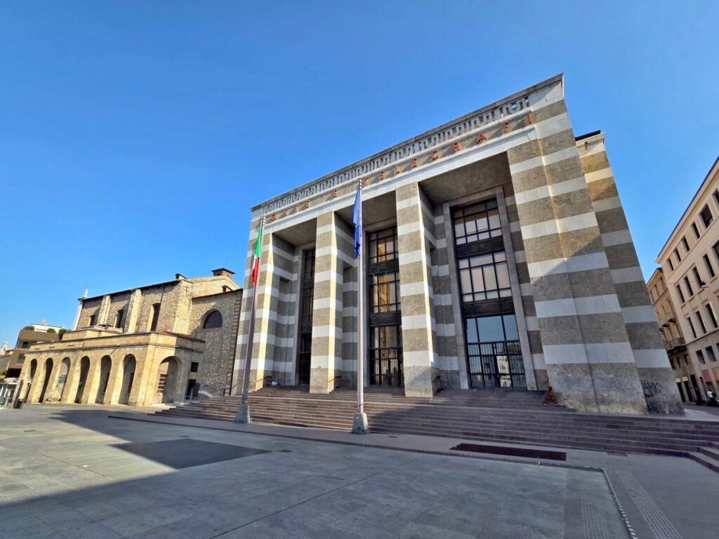 Palazzo delle Poste e Telegrafi in Brescia, Italy, with columns and Italian flags in Piazza della Vittoria