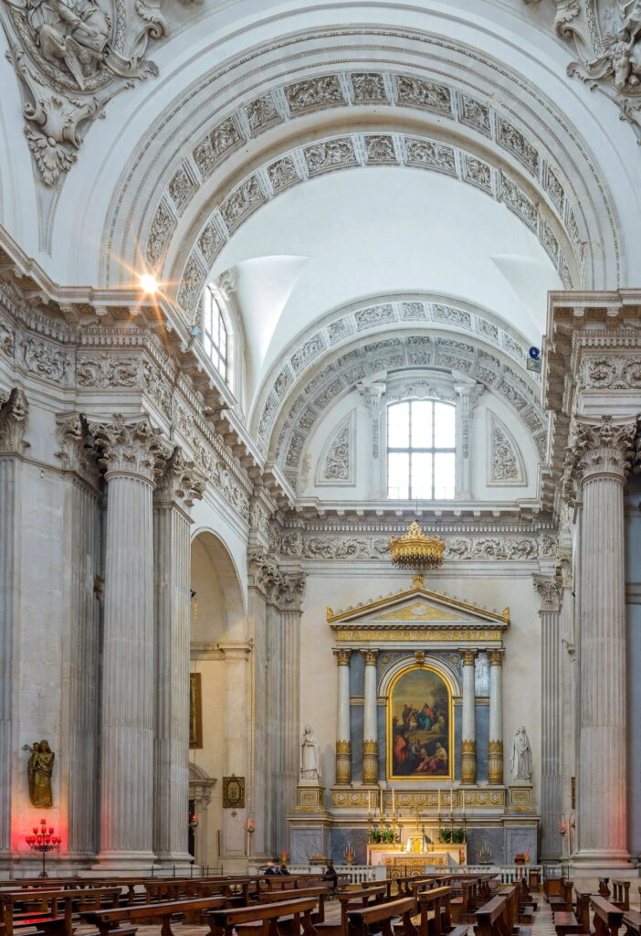 Interior of Duomo Nuovo in Brescia featuring high Corinthian columns and a side altar with religious paintings.
