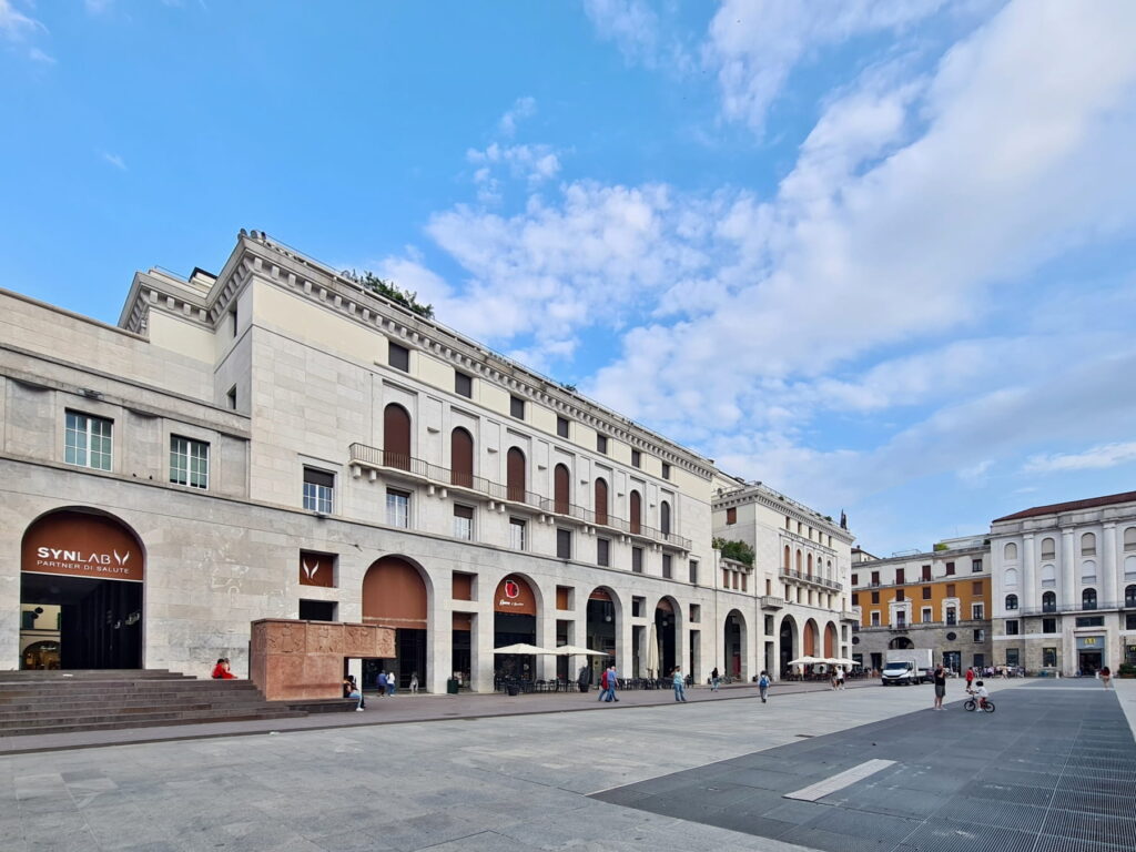 Modernist white stone buildings with long porticos in Piazza della Vittoria, Brescia, Italy.
