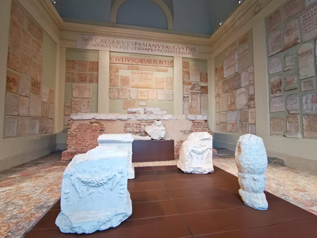 A museum gallery displaying ancient Roman stone inscriptions and carved marble fragments in Brescia.