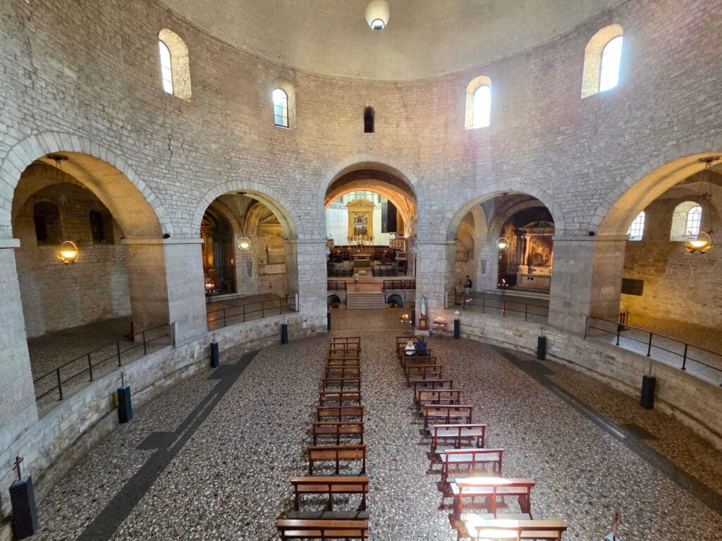 High-angle view of the circular nave and stone arches inside Duomo Vecchio in Brescia.