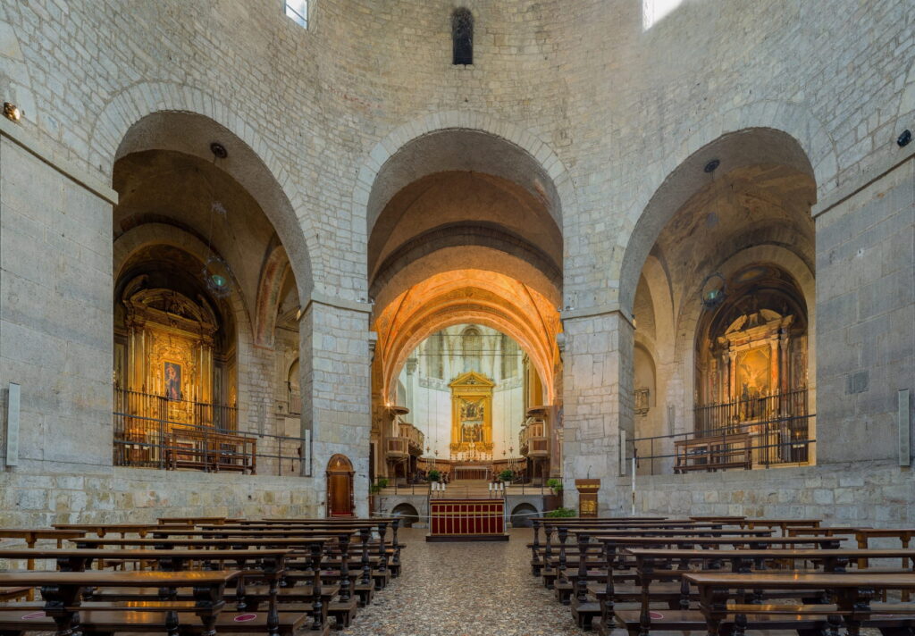 View through stone arches toward the illuminated main altar and side chapels of the Old Cathedral.
