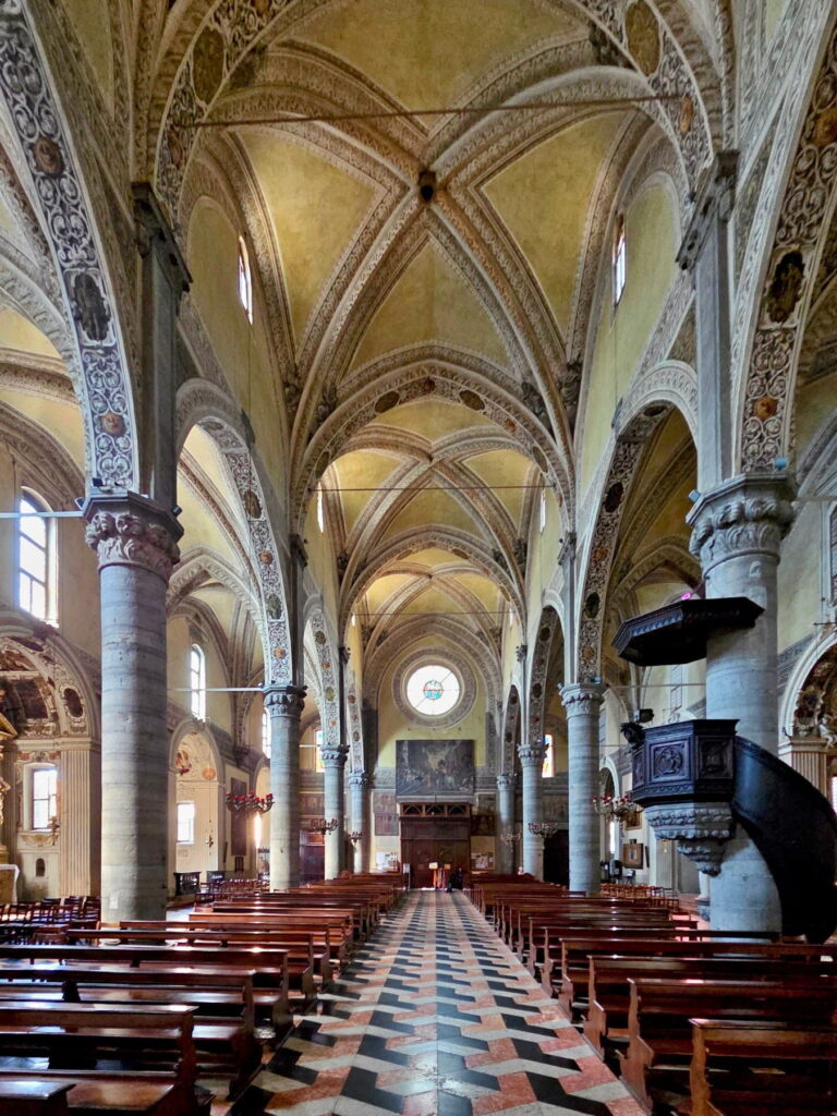 Interior view of the Salò Cathedral looking toward the entrance, showing the dark pulpit and ornate arches.
