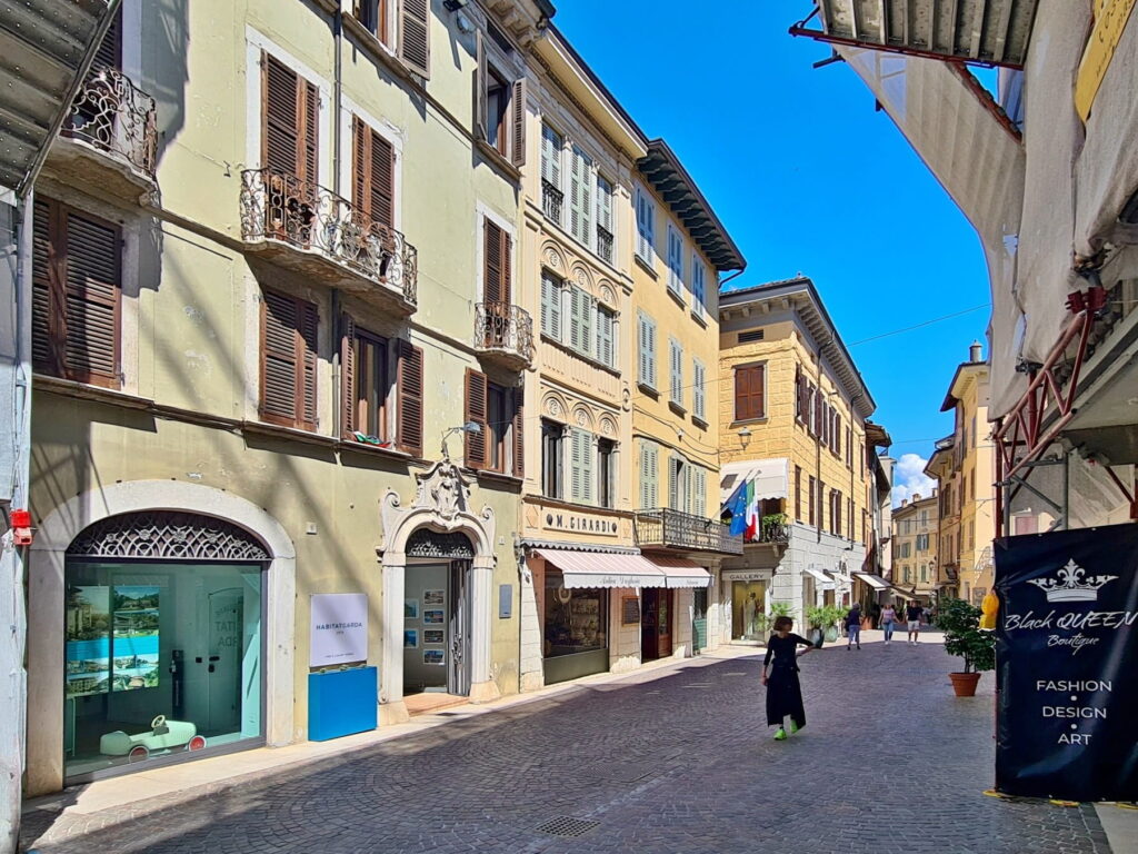 Elegant historic buildings in Salò with ornate window shutters, balconies, and boutique entrances.