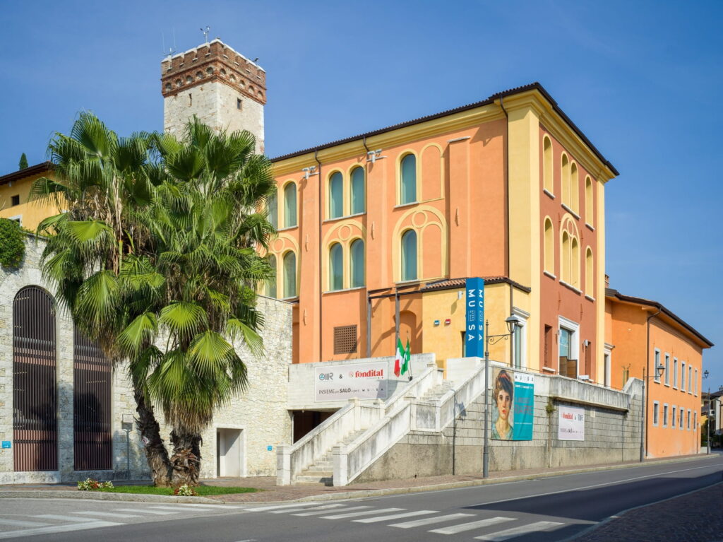 Modern white and wood-paneled building of the MuSa - Museo di Salò in Italy under a clear blue sky.
