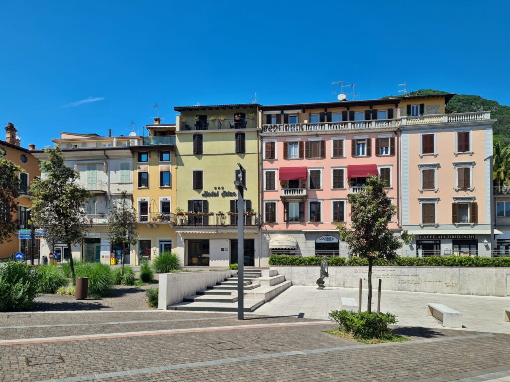 A row of pastel-colored Italian buildings and hotels lining the Piazza Vittorio Emanuele II in Salò.